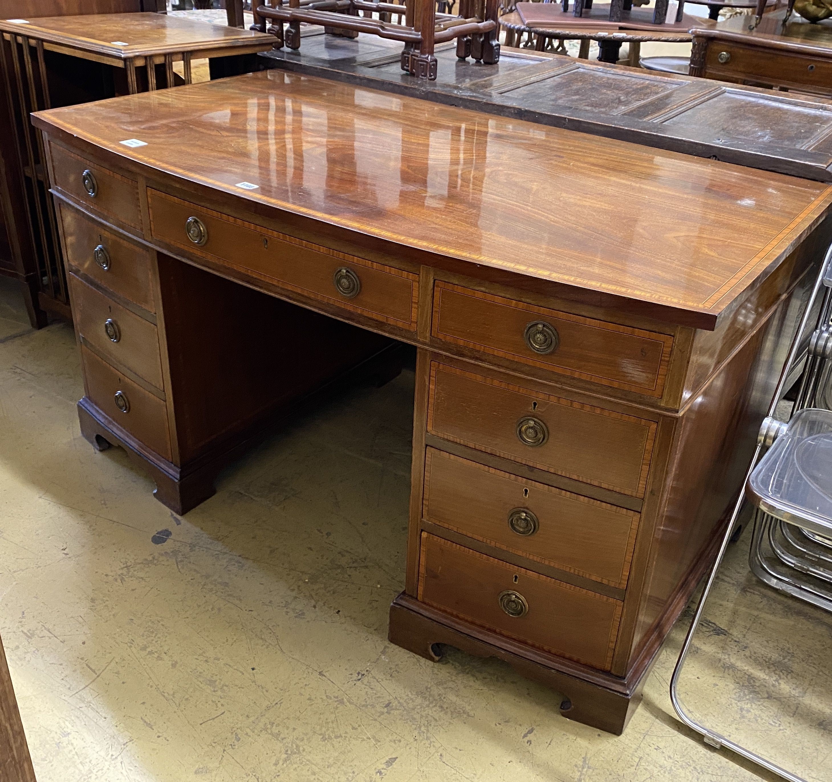 An Edwardian satinwood banded mahogany bow front kneehole pedestal desk, width 137cm, depth 76cm, height 74cm